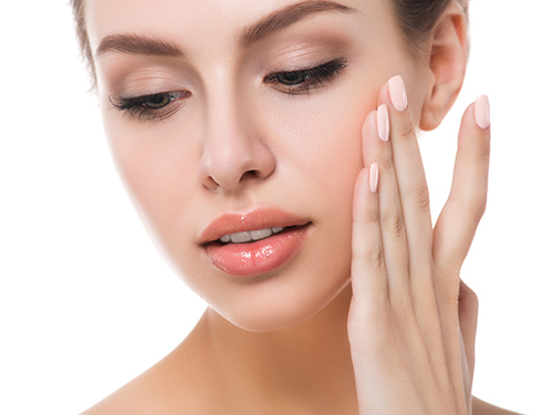 Portrait of young beautiful woman touching her face