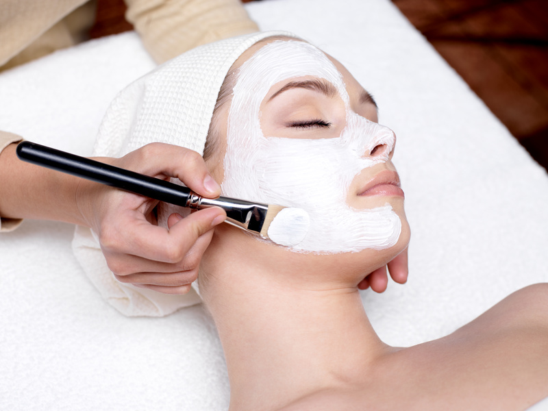 cosmetician applying facial mask on female face
